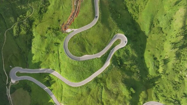 Aerial tilt up view of cars driving on the winding road of Passo Gardena in the Dolomites Mountains, Trentino, South Tyrol, Italy. Camera tilts up and reveals the mountains. LuPa Creative.