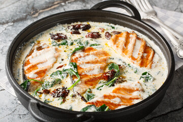 Marry Me Salmon smothered in a buttery, creamy sun-dried tomato spinach sauce closeup in the pan on...