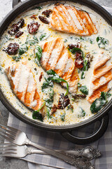 Close up of delicious tuscan cream salmon with spinach and sun-dried tomatoes in the pan on the table. Vertical top view from above