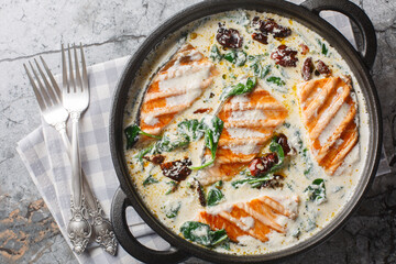 Creamy Tuscan Salmon is a simple but very richly flavoured dish with creamy garlic sauce sun-dried tomato and spinach closeup in the pan on the table. Horizontal top view from above