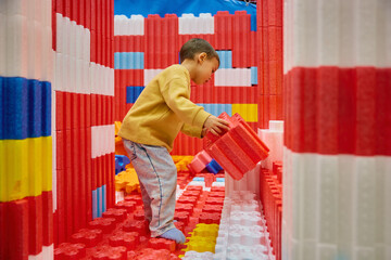 Little boy child playing with huge building blocks in entertainment center
