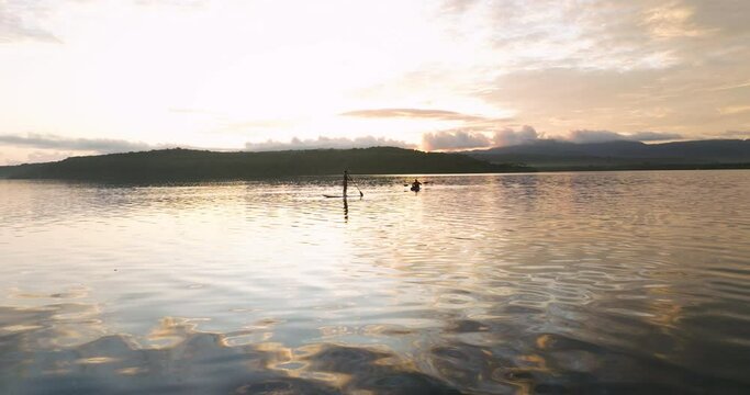 Silhouette Of People On Standup Paddleboard And Kayak At Sunrise On Moso Island In Vanuatu. wide shot