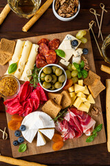 Charcuterie board with a variety of cheeses, salami, chorizzo, prosciutto, honey, grapes, nuts,...