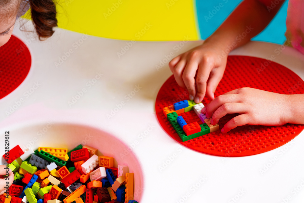 Poster child engaged in creative play with colorful building blocks on a round base