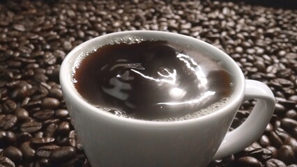 Top view of coffee or espresso with piles of coffee beans. Close up of fresh roasted coffee bean scatter around wooden table with cup of americano and aromatic stream and smoke from seed. Comestible.