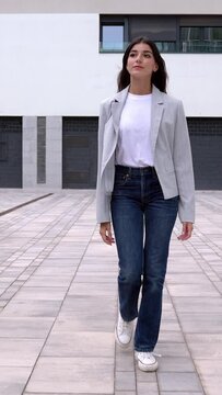 Vertical full length HD video. Front view of young confident businesswoman walking from business office building. Full body portrait of successful female entrepreneur commuting at city urban street. 
