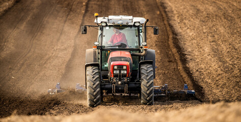 Powerful tractor with plow in action, turning the rich soil for new crops - obrazy, fototapety, plakaty
