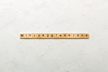 Microaggressions word written on wood block. Microaggressions text on cement table for your desing,...