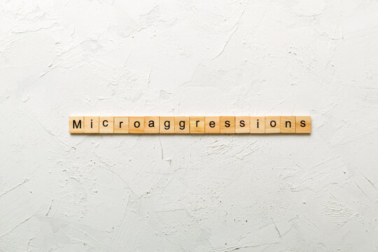 Microaggressions word written on wood block. Microaggressions text on cement table for your desing, concept