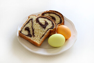 Cozonac, pane dolce tradizionale rumeno con noci e due uova di Pasqua isolate su sfondo bianco. Concetto di vacanza di Pasqua. - 782840055