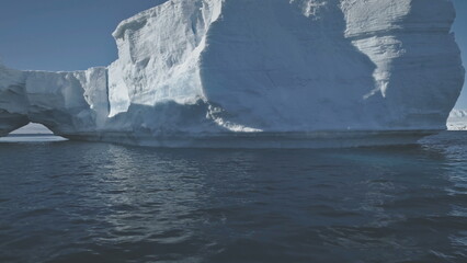 Antarctica Aerial Flight Over Polar Ocean To Iceberg. Amazing Winter Scenery. Huge Sunlit Ice Mountain Among Cold Antarctic Ocean. Massive Iceberg With Arch. Winter Landscape. Wilderness.