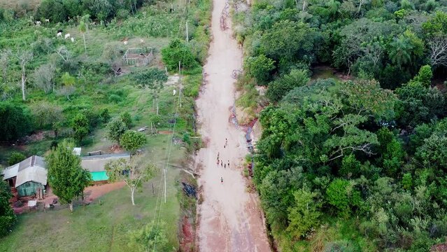 Aerial Following A Road That Goes Over The Paraguay Forest With Children Walking Uphill Back To Their Homes.