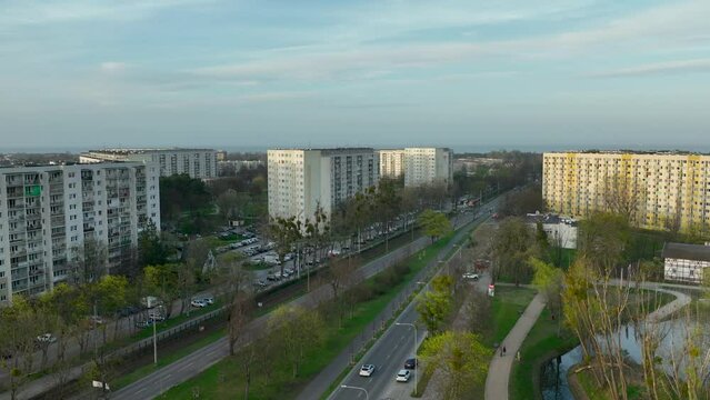 aerial view of a suburban residential area in Żabianka, Gdańsk, with large apartment buildings flanking a road amidst green spaces and trees, under a soft evening sky.