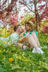 Fototapeta premium close-up portrait young couple, enjoying picnic in park, sharing apple. It concept of strong family bonds, harmonious relationships. radiates love, togetherness, strength of their connection.