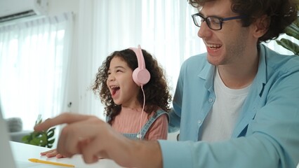 Caucasian dad put headphones on daughter while girl learning code. Father take care schoolgirl...