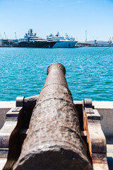 Eine alte Kanone im Hafen, im Hintergrund liegen Luxusyachten vor Anker, Tarragona, Spanien