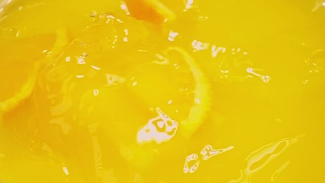 close up of natural orange slices falling in juice, advertising of tropical fruit juice splashing, super slow motion