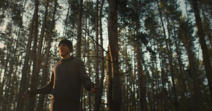Man training in the forest. Outdoor rope skipping jumping on sunrise in the wood. Young athete morning healthy lifestyle