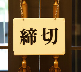 A sign with a deadline written in Japanese on the handle of the entrance door of the building