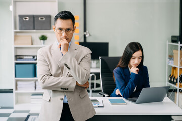 Young attractive Asian male office worker business suits smiling at camera in office