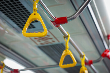 Selective focus on yellow hanging handle grip on public transportation such as bus and train, down view angle