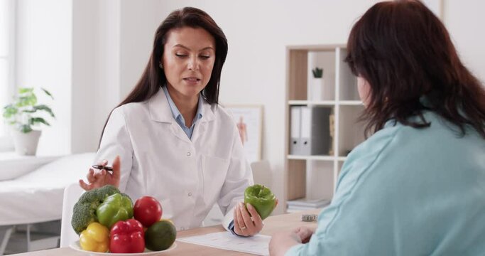 nutritionist doctor consulting overweight patient, providing advice on healthy eating plan and creating a diet program. They discussing the importance of including vegetables in the diet.