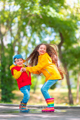 Happy kids girl and boy with colorful rubber rain boots playing outdoor and jumping in a rainy puddle - 782872418