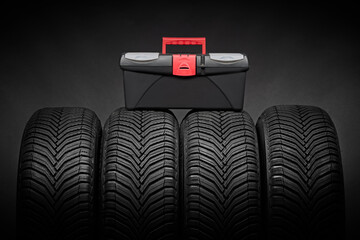 Car tires, winter tyres with toolbox case with instruments for car repair isolated on black background