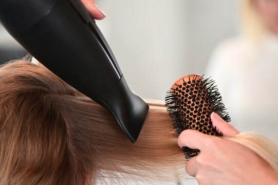 Hair stylist brushing and drying blonde hair with a special technique
