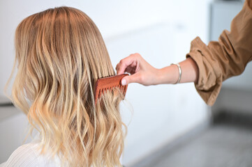 Stylist Combing Through Blonde Highlighted Wavy Hair