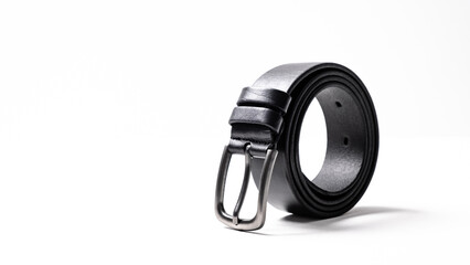 Twisted black leather belt with matted metal buckle isolated on white background. Fastened fashionable unisex, man or woman accessory for trousers, jeans, dress. Male luxury strap. Haberdashery goods