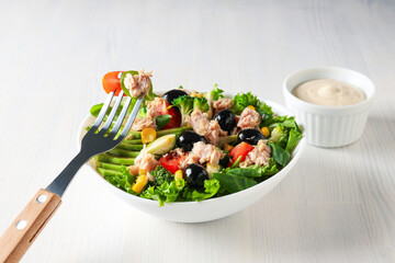 Salad with tuna on a white table.