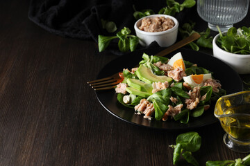 Salad with tuna on a dark table with a fork.