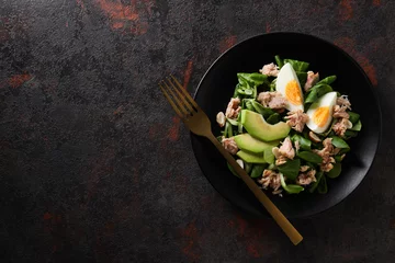  Salad with tuna on a dark table with a fork. © Atlas
