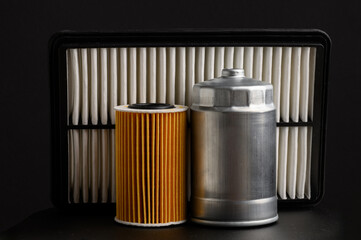 Car oil filter, air filter and fuel filter on black background, close-up. Auto parts replacement...