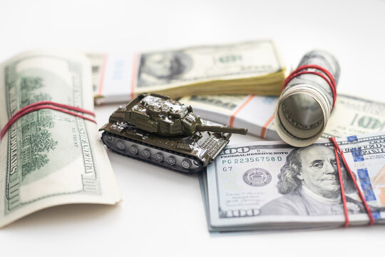 Toy tank on US hundred dollar bills banknotes close up. The concept of war costs, military spending and economic crisis