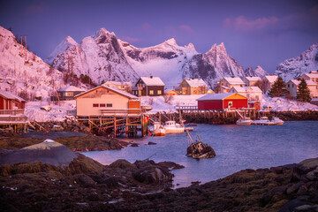 Norwegian fishing village with red rorbu houses, mountain peaks and sea coast winter landscape, Lofoten islands, Norway - 782898865