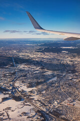 Airplane flying low over snowy mountains and preparing for landing to the airport, view from plane window of wing turbine and skyline