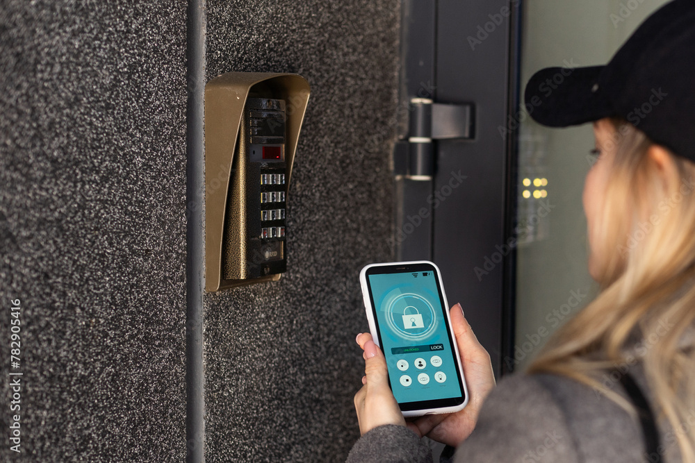 Poster woman locking smartlock on the entrance door using a smart phone. concept of using smart electronic 