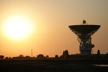Photo of a large space telescope and antenna at sunset.