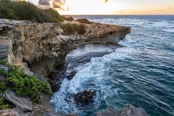 The sun slowly rises over jagged cliffs, meeting the rough turquoise waters of the Pacific Ocean...