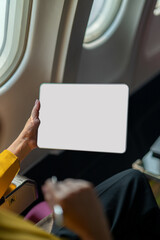 An over-the-shoulder view of a businesswoman using a laptop on an airplane, capturing the essence of modern travel and work flexibility.