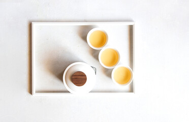 Top view of minimalist composition with Oriental Tea set, teapot , cups and tea leaves on white frame - 782911066