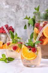 Summer Sangria cocktail or lemonade with raspberry, orange and mint. Refreshing organic non-alcoholic, Detox vitaminized healthy drink, fruit in a in a glass. Quench your thirst on a hot day.