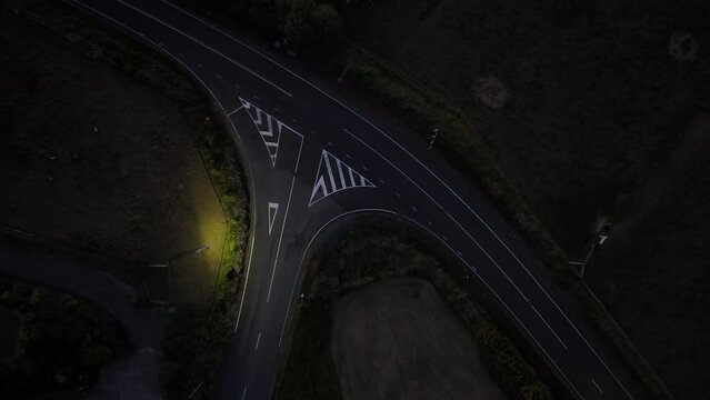 Road junction at night with a car passing.  Single street light.