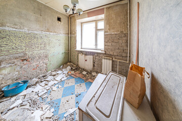 Renovation in a small kitchen in an old apartment. Old broken removed ceramic tiles, construction debris, crooked ugly wall. Dirt, dust, mortar, cement must be taken to a special site for recycling.
