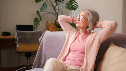 Mature old 60s woman, older middle aged female resting on couch taking deep breath of fresh air...