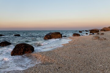 Fototapeta premium Beautiful view of rocks on a beach with clear sky during sunset