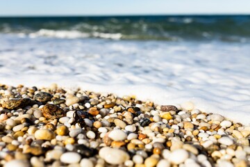 Pebbles and white snow covering seashore