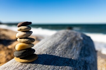 Stack of balanced stones arranged on tree trunk surface by the sea